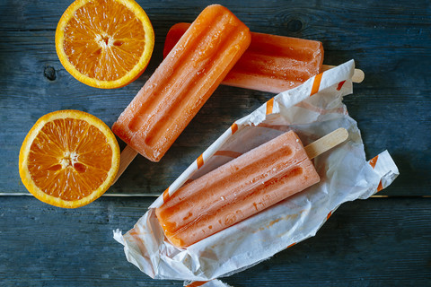 Orangenschnee-Eis in Verpackungen und Orangen auf Holz, lizenzfreies Stockfoto