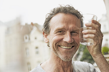 Porträt eines lächelnden Mannes, der mit einem Wasserglas anstößt - FMKF002753