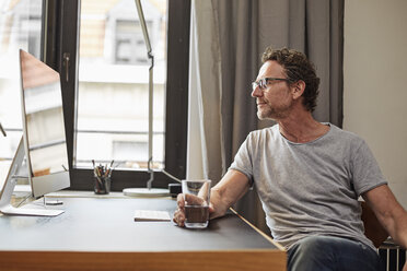 Man sitting at desk looking at computer - FMKF002755