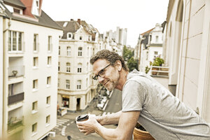 Lächelnder Mann auf Balkon mit Blick nach unten - FMKF002756