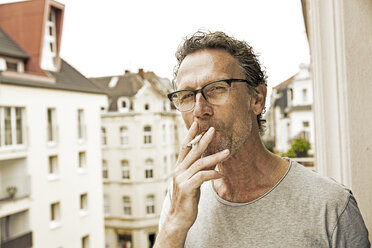 Portrait of man smoking on balcony - FMKF002759