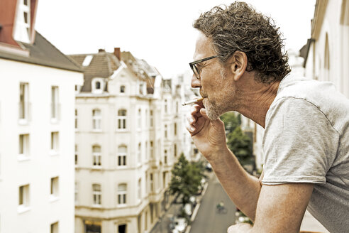 Mann rauchend auf Balkon - FMKF002760