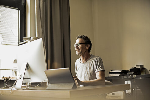 Man sitting at desk working with computer - FMKF002764