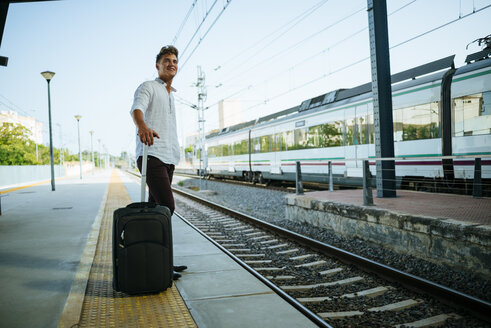 Junger Mann mit Koffer wartet am Bahnsteig - KIJF000530