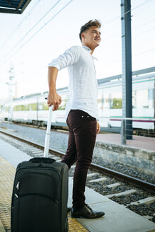 Junger Mann mit Koffer wartet am Bahnsteig - KIJF000531