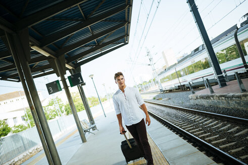 Junger Mann mit Koffer auf dem Bahnsteig - KIJF000532