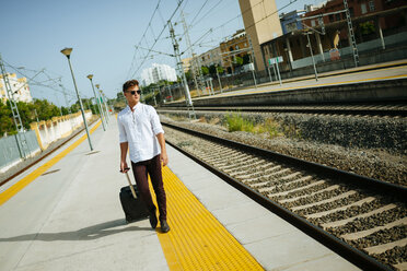 Junger Mann mit Koffer auf dem Bahnsteig - KIJF000537