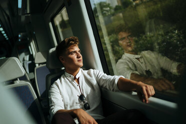 Junger Mann schaut aus dem Fenster eines Zuges - KIJF000542