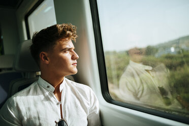 Junger Mann schaut aus dem Fenster eines Zuges - KIJF000545