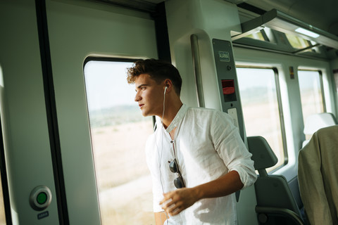 Junger Mann schaut aus der Tür eines Zuges, lizenzfreies Stockfoto