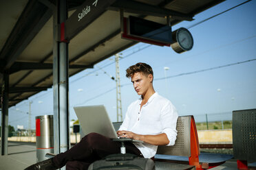 Junger Mann benutzt einen Laptop am Bahnsteig - KIJF000555
