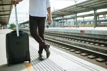 Man with suitcase waiting at station platform - KIJF000562