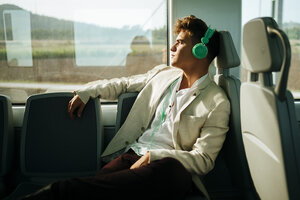 Junger Mann hört Musik in einem Zug - KIJF000572