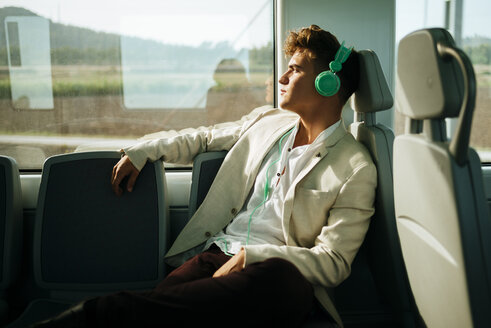 Young man listening to music on a train - KIJF000572