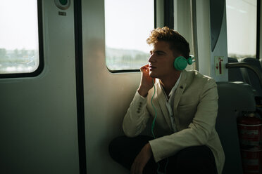 Junger Mann hört Musik in einem Zug - KIJF000574