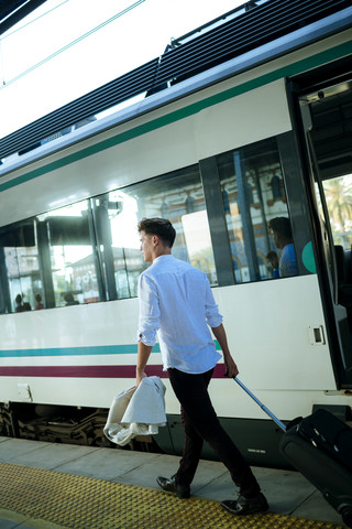 Junger Mann verlässt den Zug auf einem Bahnhof, lizenzfreies Stockfoto