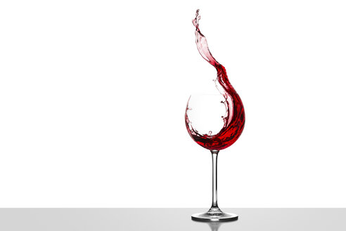 Red wine splashing in glass in front of white background - CPF000031