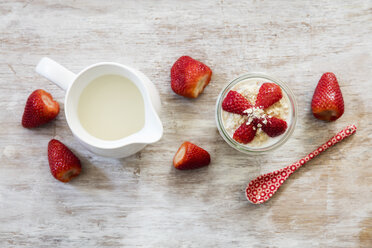 Glas Overnight Oats mit Erdbeeren und Milchkännchen auf Holz - EVGF003019