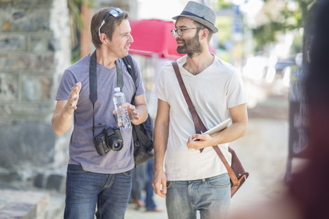 Zwei Männer, die in der Stadt spazieren gehen und sich unterhalten, lizenzfreies Stockfoto