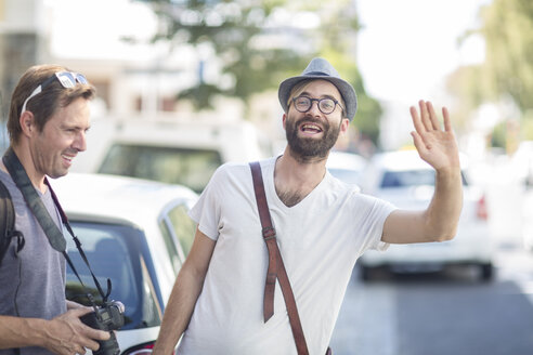 Mann mit Freund in der Stadt, der ein Taxi ruft - ZEF008975