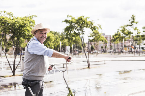 Smiling senior man with folding bicycle - UUF008041