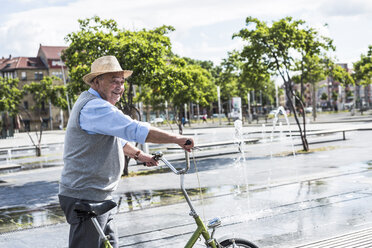Smiling senior man with folding bicycle - UUF008042