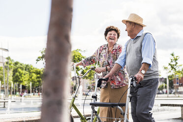 Senior couple with bicycle and wheeled walker - UUF008045