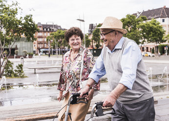 Senior man using wheeled walker for strolling with his wife - UUF008047