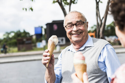 Porträt eines glücklichen älteren Mannes mit Eiswaffel, der seine Frau ansieht - UUF008055