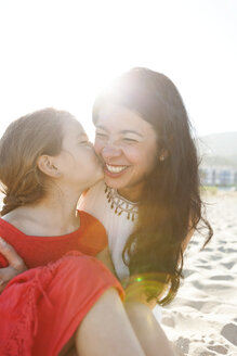 Little girl kissing her mother on the beach - VABF000680