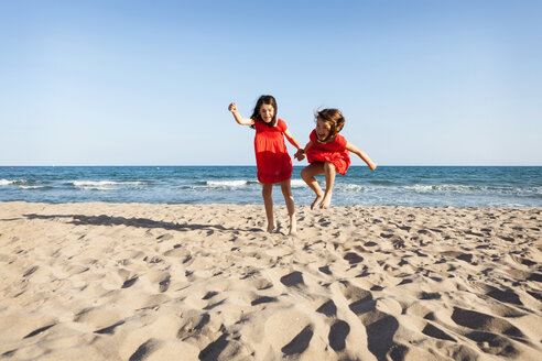 Two little sisters jumping together on the beach - VABF000682