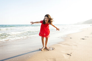 Portrait of happy little girl playing on the beach at seafront - VABF000685