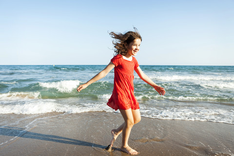 Glückliche kleine Schwestern, die am Ufer des Strandes spazieren gehen, lizenzfreies Stockfoto