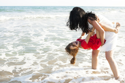 Mutter spielt mit ihrer kleinen Tochter an der Strandpromenade, lizenzfreies Stockfoto