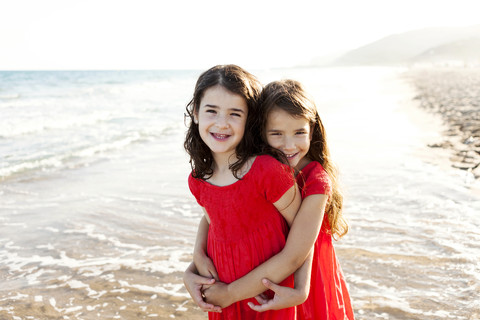 Two happy little sisters standing at seafront stock photo