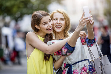 Zwei glückliche junge Frauen machen ein Selfie in der Stadt - GDF001053