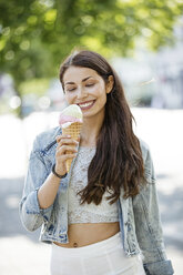 Smiling young woman holding ice cream cone - GDF001058