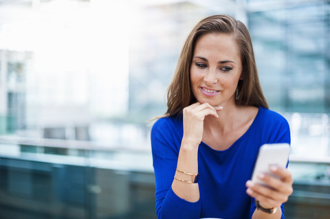 Smiling brunette woman looking at cell phone stock photo