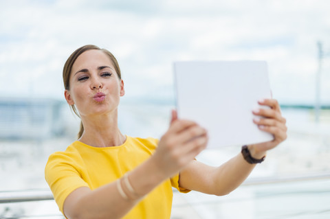 Brünette Frau nimmt ein Selfie mit digitalem Tablet, lizenzfreies Stockfoto