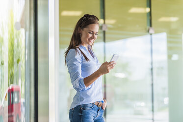 Smiling brunette woman looking at cell phone - DIGF000628