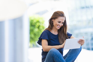 Smiling brunette woman using digital tablet - DIGF000634