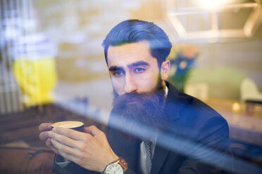 Fashionable man with beard sitting in coffee shop, drinking coffee - NAF000013