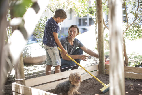 Vater und Sohn mit Hund im Garten - ZEF009003