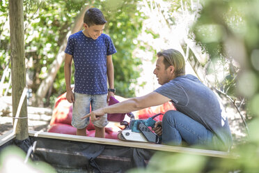 Vater und Sohn bauen gemeinsam einen Sandkasten im Garten - ZEF009020