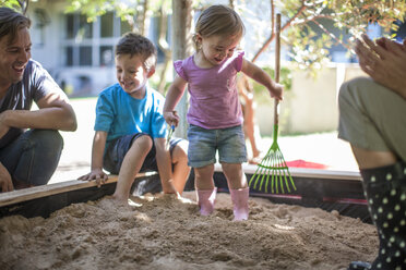 Mädchen mit Familie spielt im Sandkasten - ZEF009027