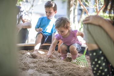 Mädchen mit Familie spielt im Sandkasten - ZEF009028