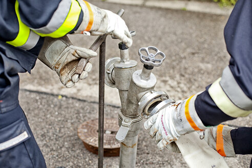 Nahaufnahme von Feuerwehrleuten, die einen Schlauch an einen Hydranten anschließen - MAEF011870