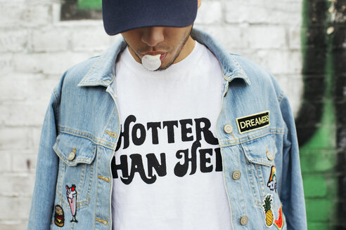 Junger Mann mit Kaugummiblase und T-Shirt mit der Aufschrift 