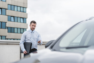 Businessman opening car on parking lot - DIGF000641