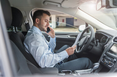 Geschäftsmann mit Dokumenten auf dem Handy im Auto - DIGF000648